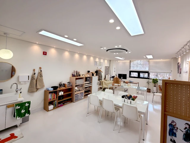 세면대와 앞치마, 여러 작업 테이블과 창이 보이는 넓은 교실